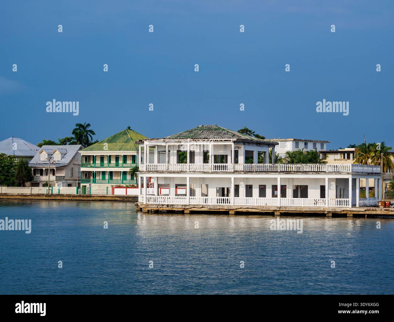 Historic buildings along the waterfront in Belize City with calm waters and blue sky Stock Photo