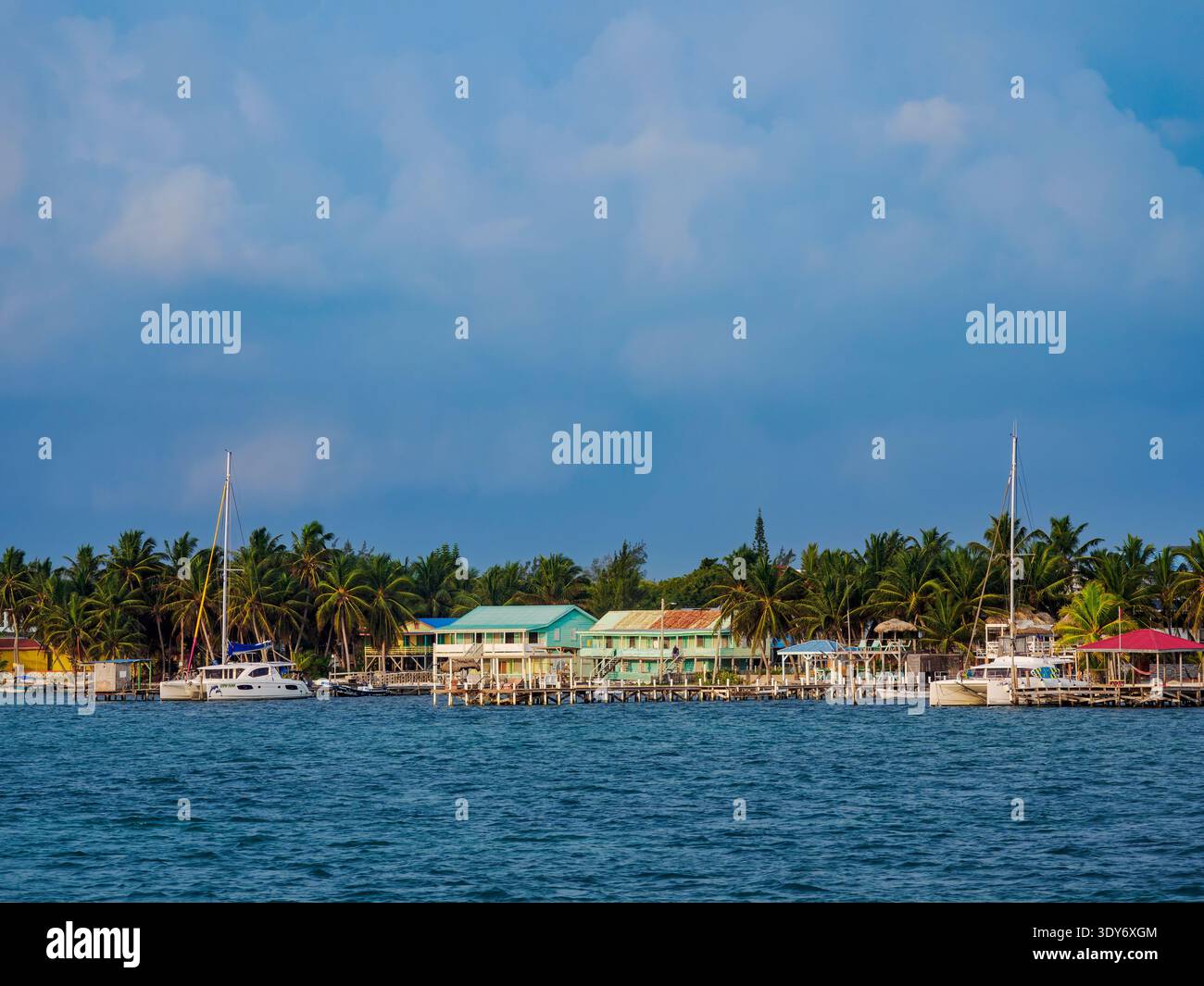 Waterside scene on Caye Caulker featuring boats and buildings along the shore in Belize District Stock Photo