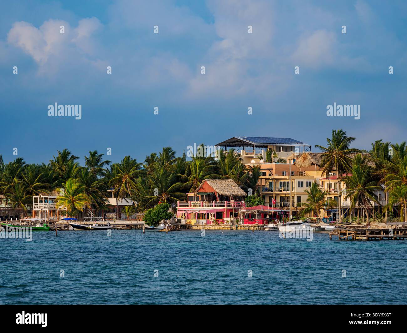 Waterfront scene in Caye Caulker showing buildings and boats with palm trees in the background Stock Photo