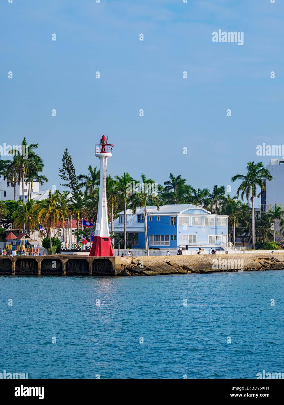 Baron Bliss Lighthouse stands tall near the waterfront in Belize City with palm trees and nearby buildings Stock Photo