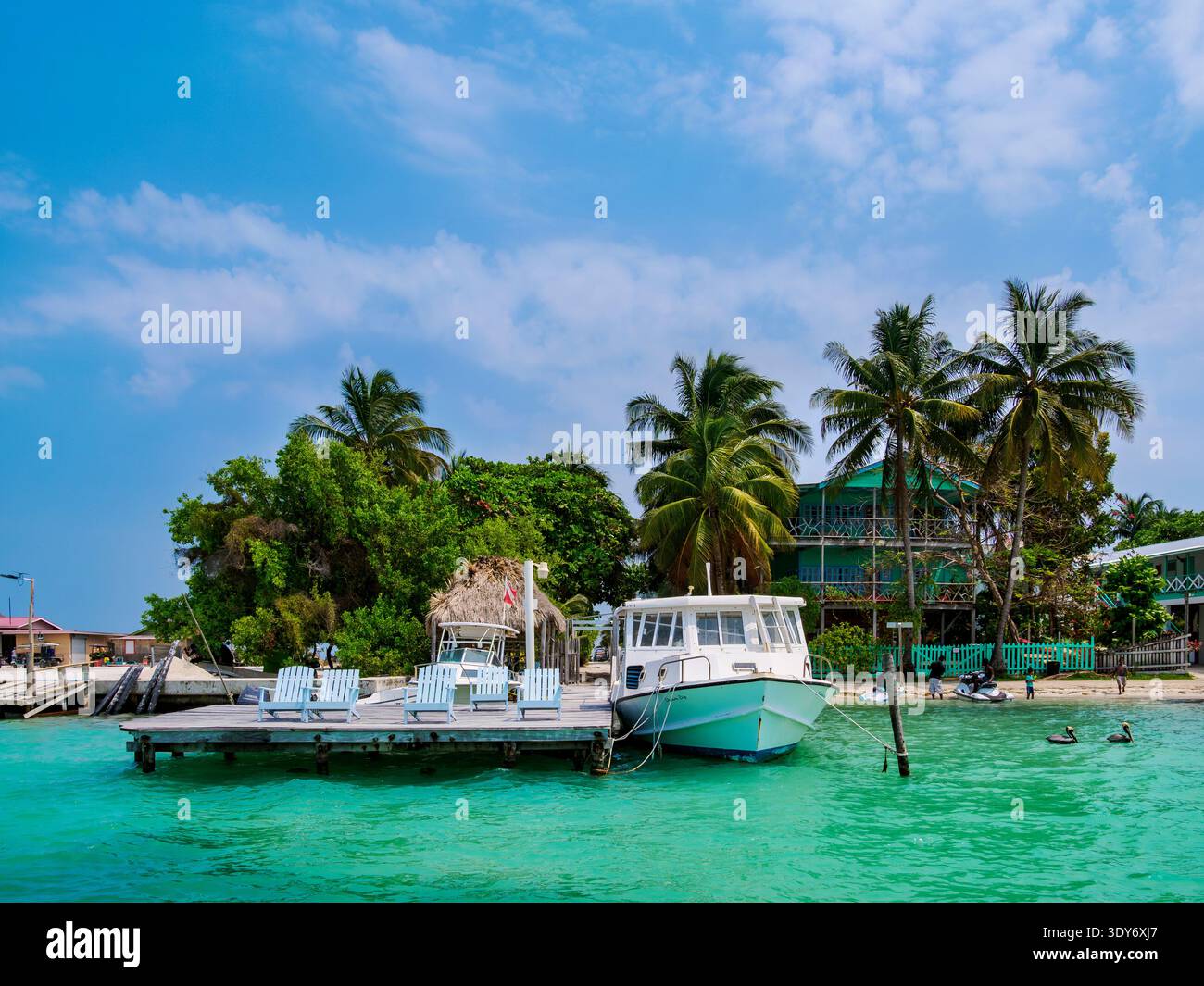 Bright waterfront scene in Caye Caulker showing boats and trees on a sunny day in Belize Stock Photo
