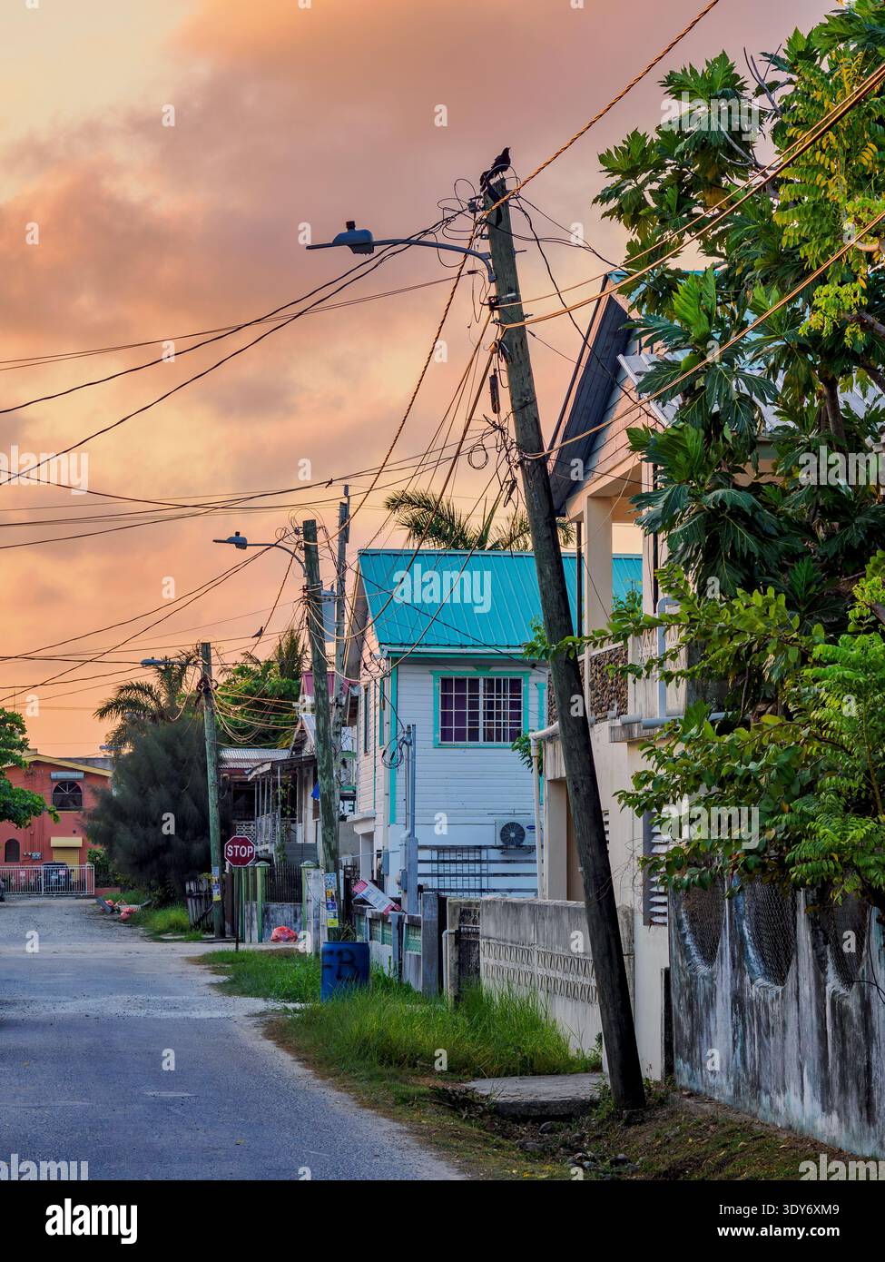 Colorful sunset over Belize City street with power lines and houses in Belize District Stock Photo