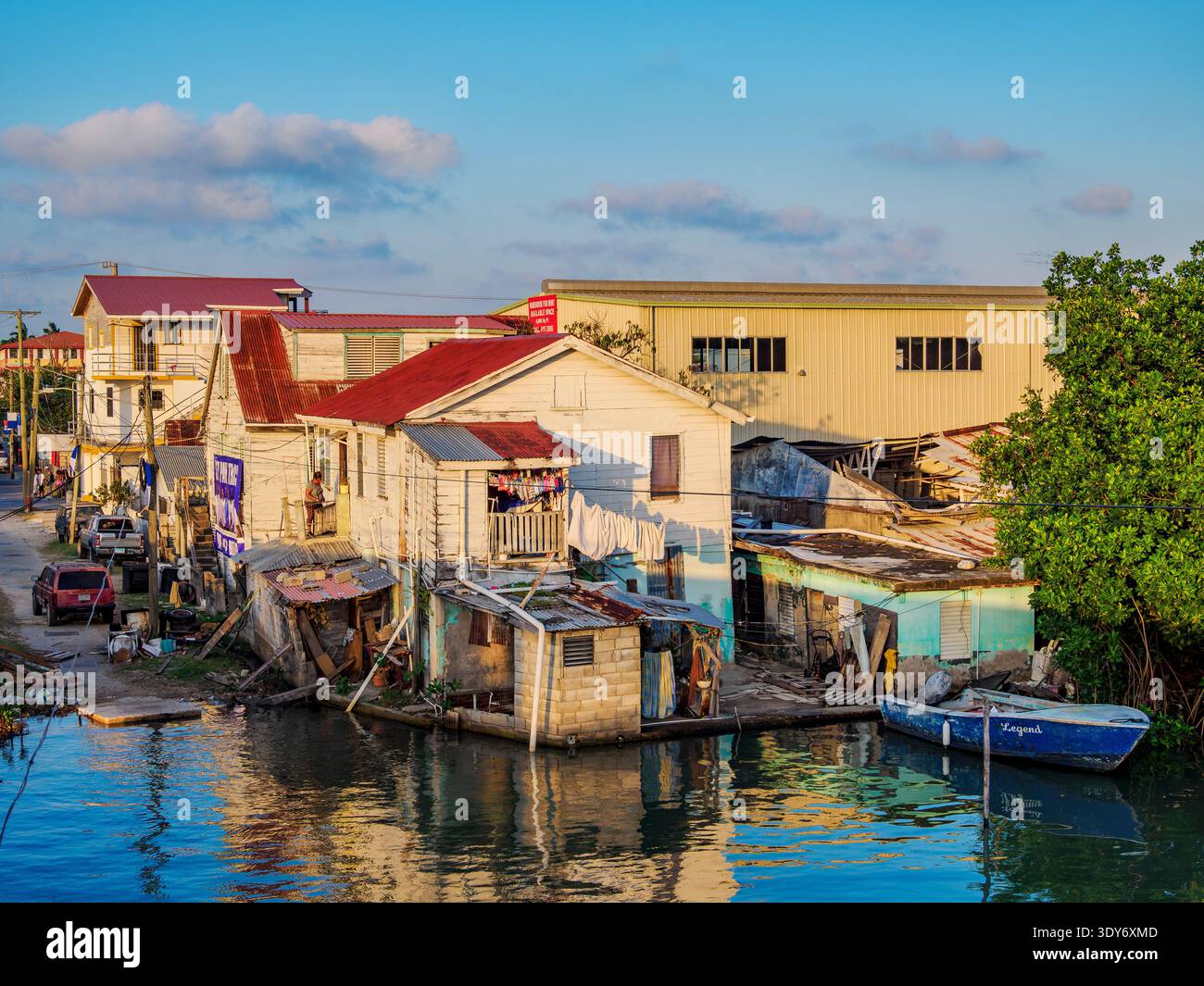 Sunset view of Haulover Creek with houses and a boat in Belize City, Belize Stock Photo