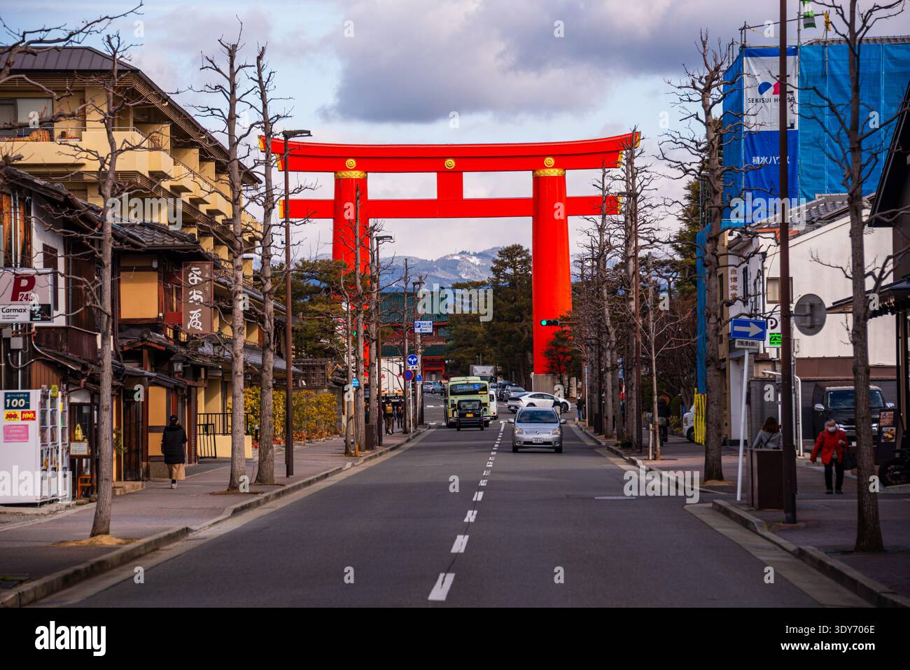 Urban street scene in Kyoto with a bright red torii gate spanning the ...