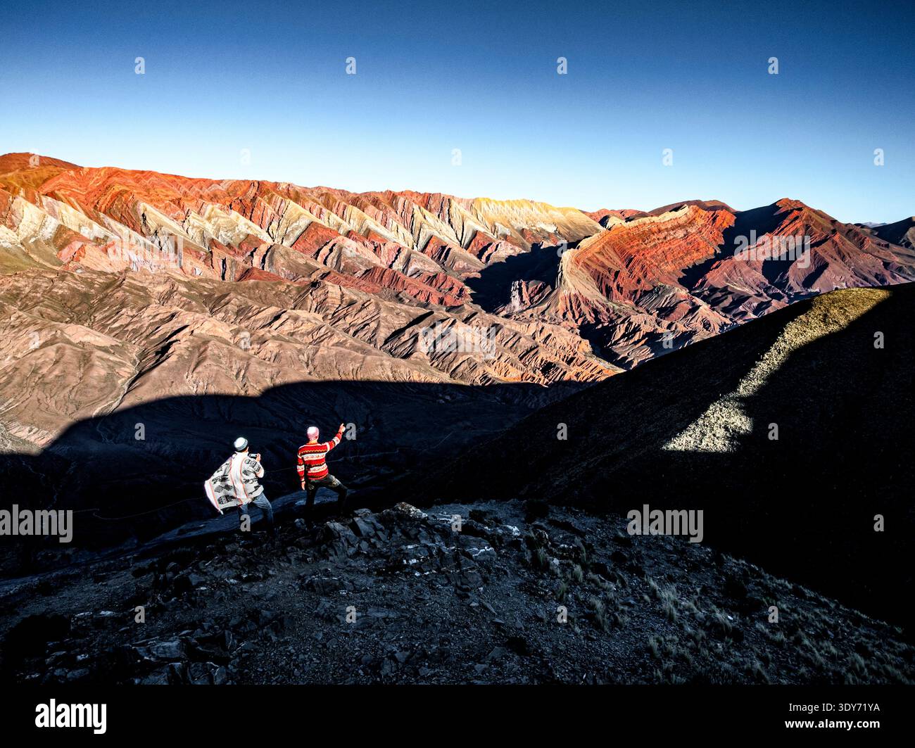 Hikers explore the colorful mountain range in Humahuaca, Jujuy, Argentina, capturing nature's beauty in their journey Stock Photo