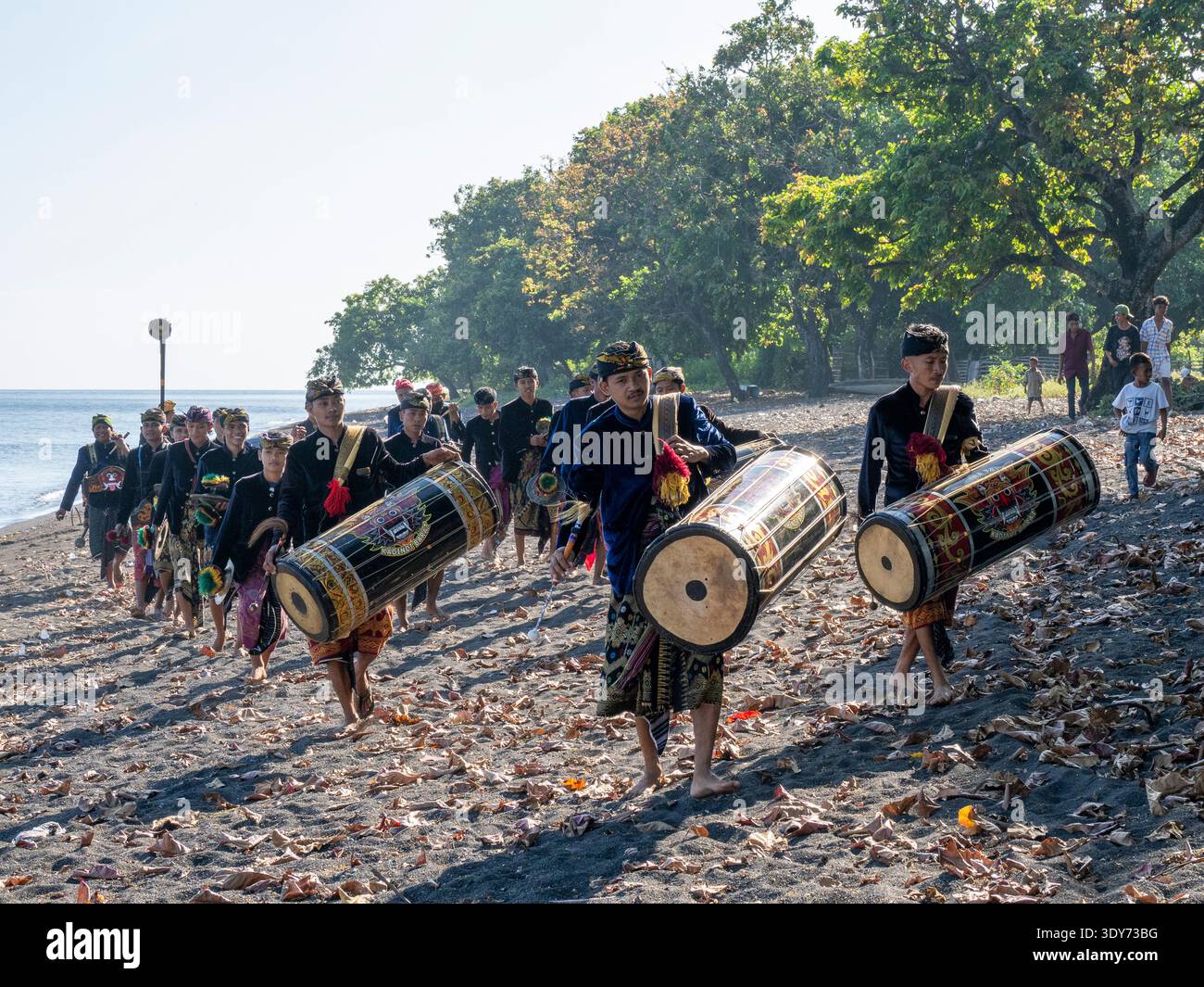 Ceremonial drummers walk on the beach with painted drums in Indonesia for a traditional performance Stock Photo