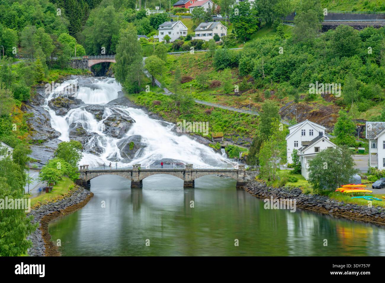 View of Hellesylt waterfall flowing down rocks near houses and bridge in Hellesylt, Stranda Municipality, Norway Stock Photo