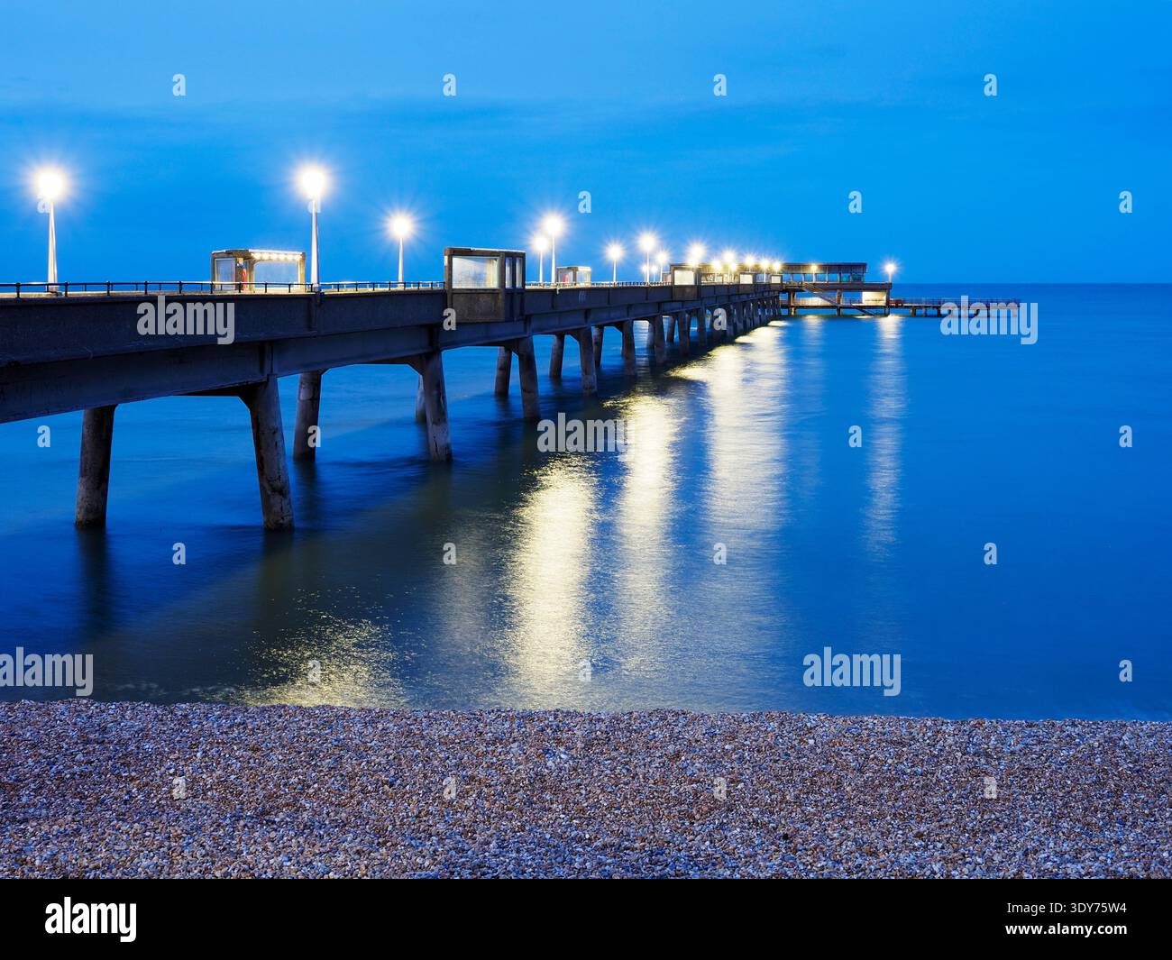 View of pier with lights reflecting on water at dusk in Deal, Kent, United Kingdom Stock Photo