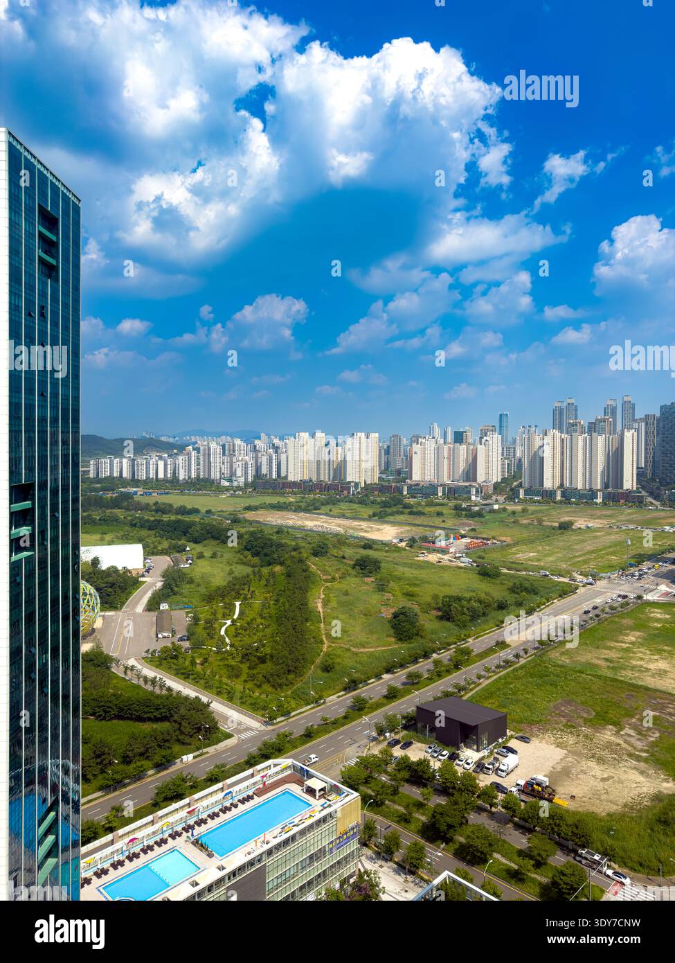 Modern city skyline with residential buildings, roads and green space under blue sky, urban development and real estate concept. - Smartphone Captured Stock Image