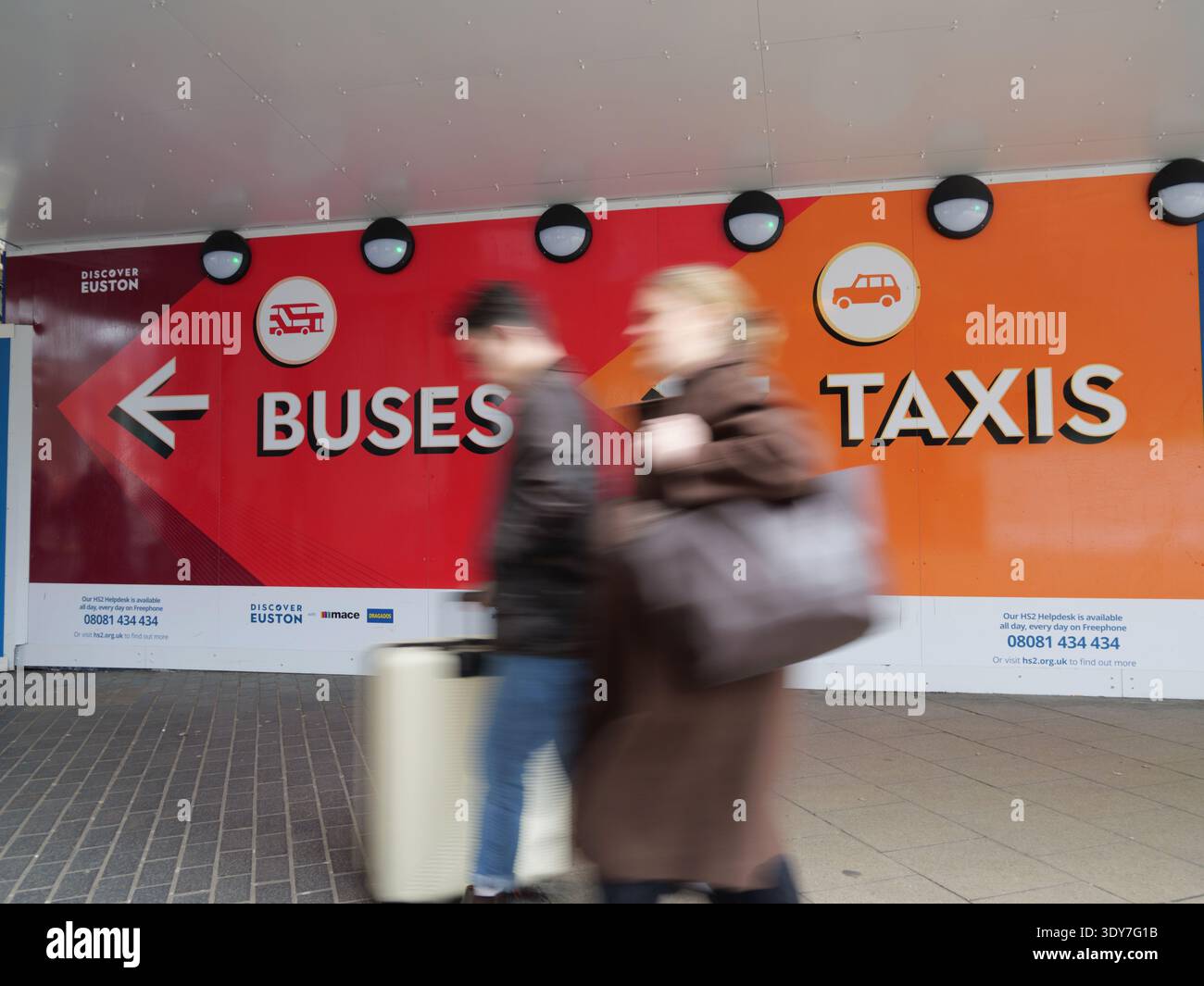Exterior view of pedestrians and commuters moving with motion blur past ...