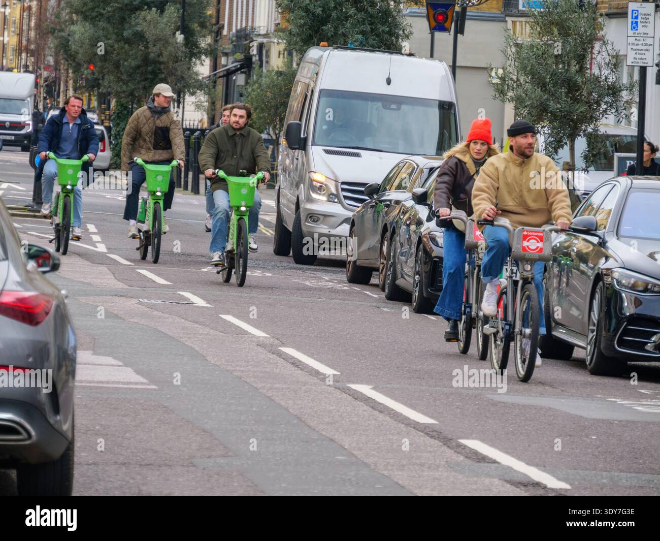 Exterior view of a group of six rental cyclists riding down a street in ...