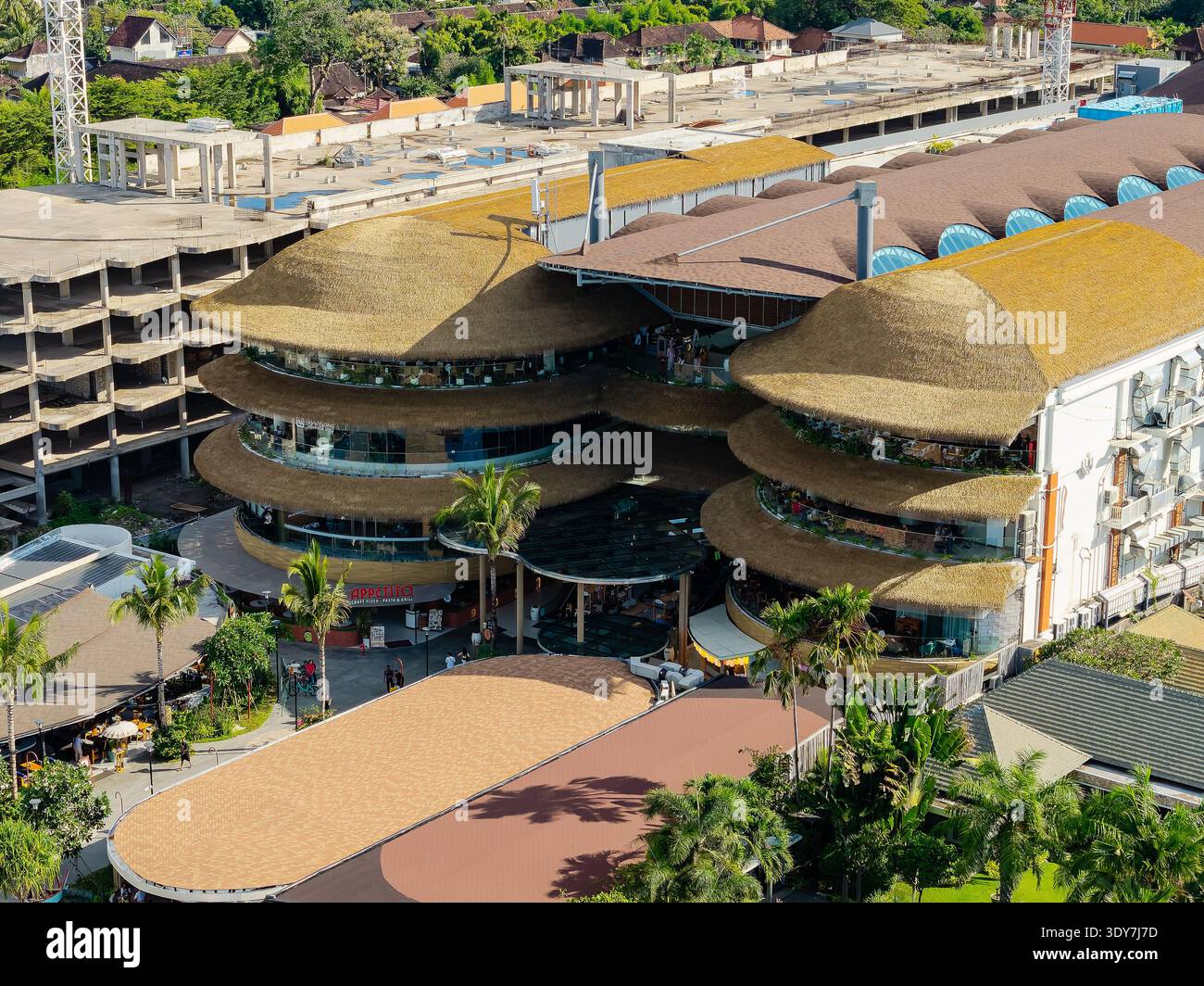 Exterior of Icon Bali mall featuring unique thatched roof design and palms Stock Photo