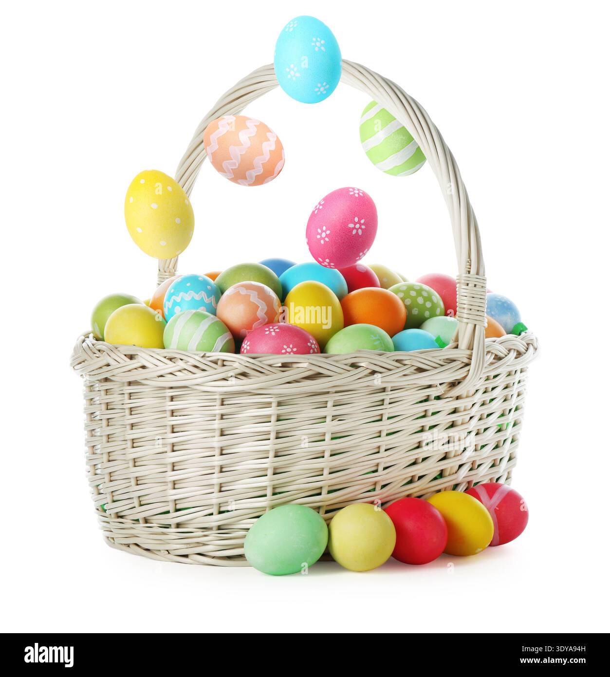 Bright Easter eggs falling into basket on white background Stock Photo