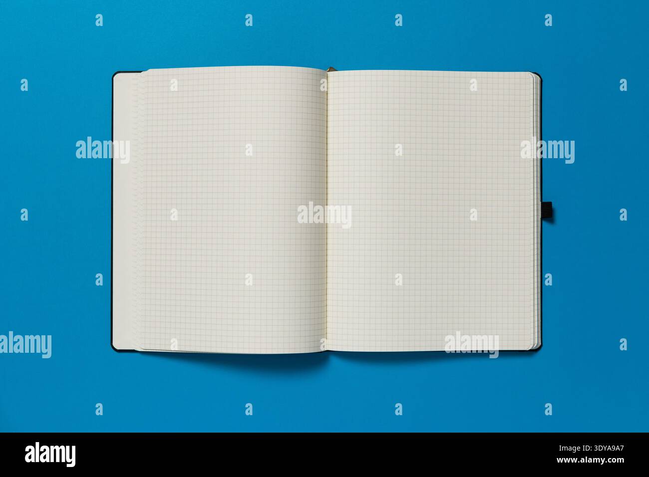 Open notepad on a blue background. The page is blank. Stock Photo