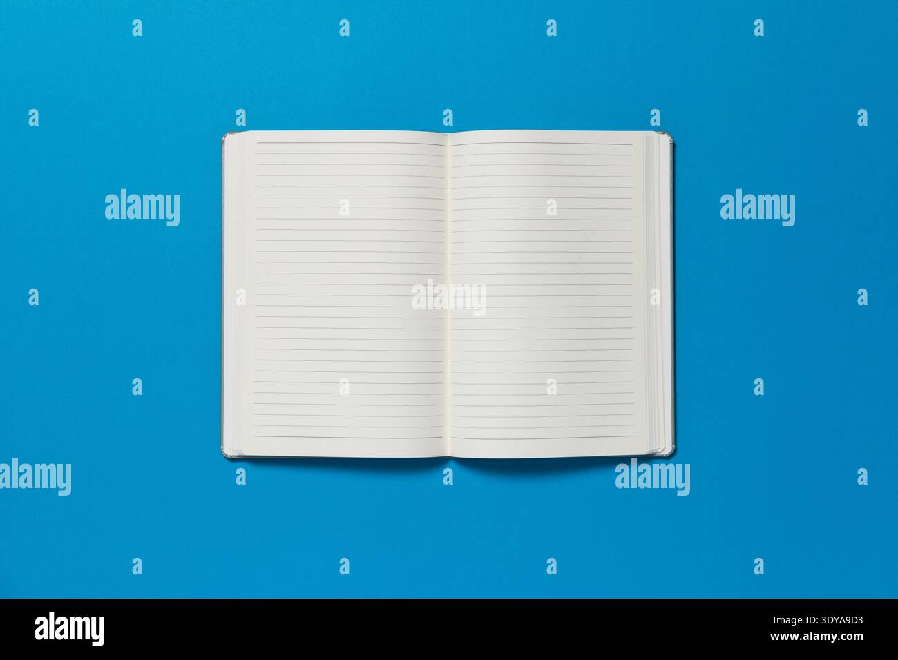 Open notepad on a blue background. The page is blank. Stock Photo