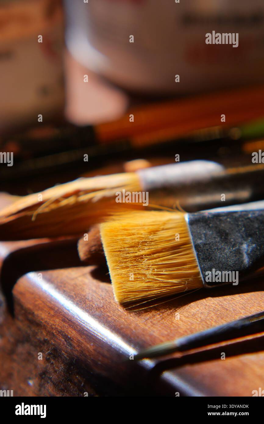 Brushes and tools on wooden surface in art space Stock Photo
