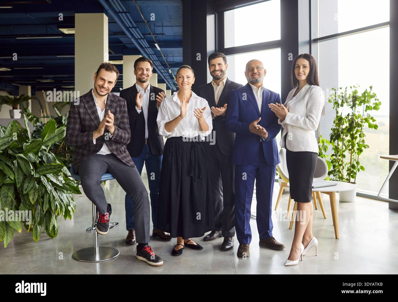 Happy business team clapping hands, smiling on meeting in open space office Stock Photo