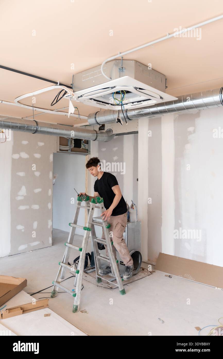 Hvac technician installing air conditioning unit during construction Stock Photo