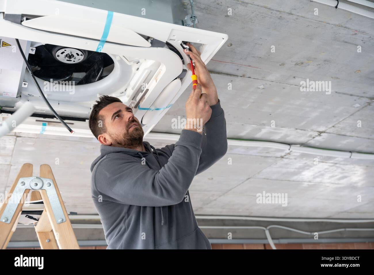 Hvac technician installing air conditioning ceiling unit in building Stock Photo