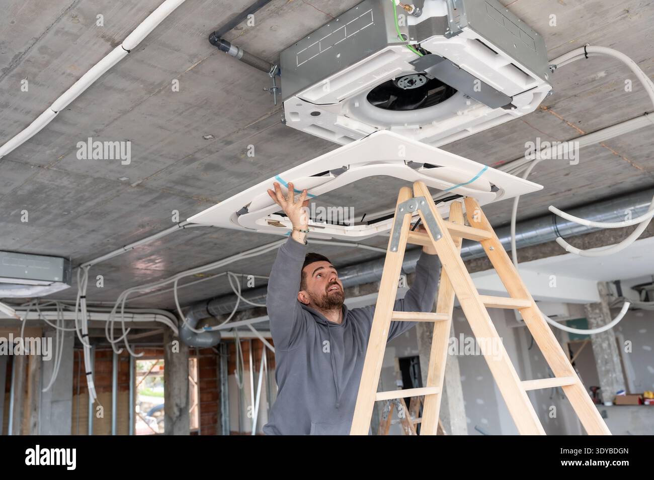 Technician installing rooftop air conditioning unit on construction ceiling Stock Photo