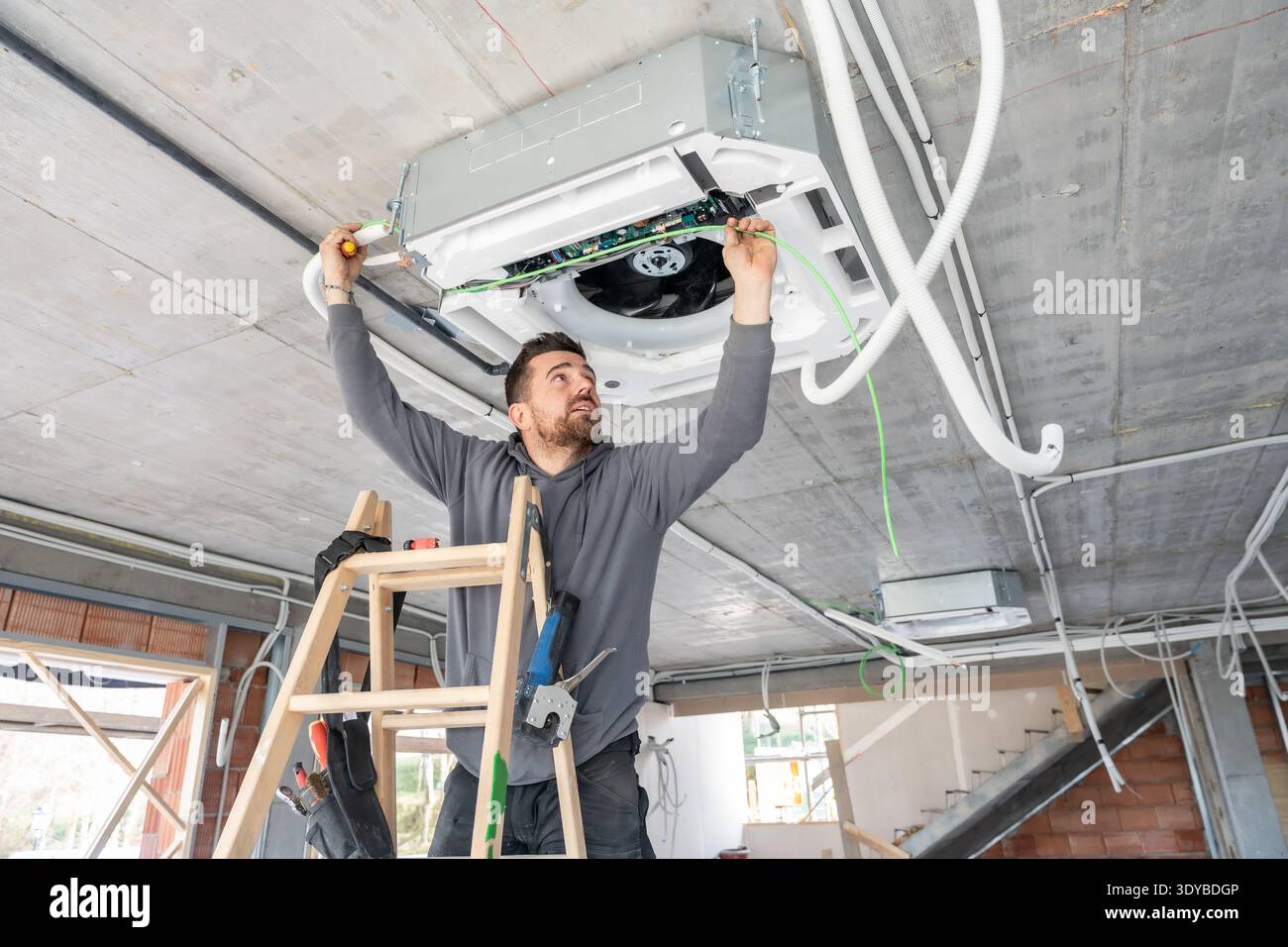 Air conditioning technician installing hvac system on ceiling Stock Photo