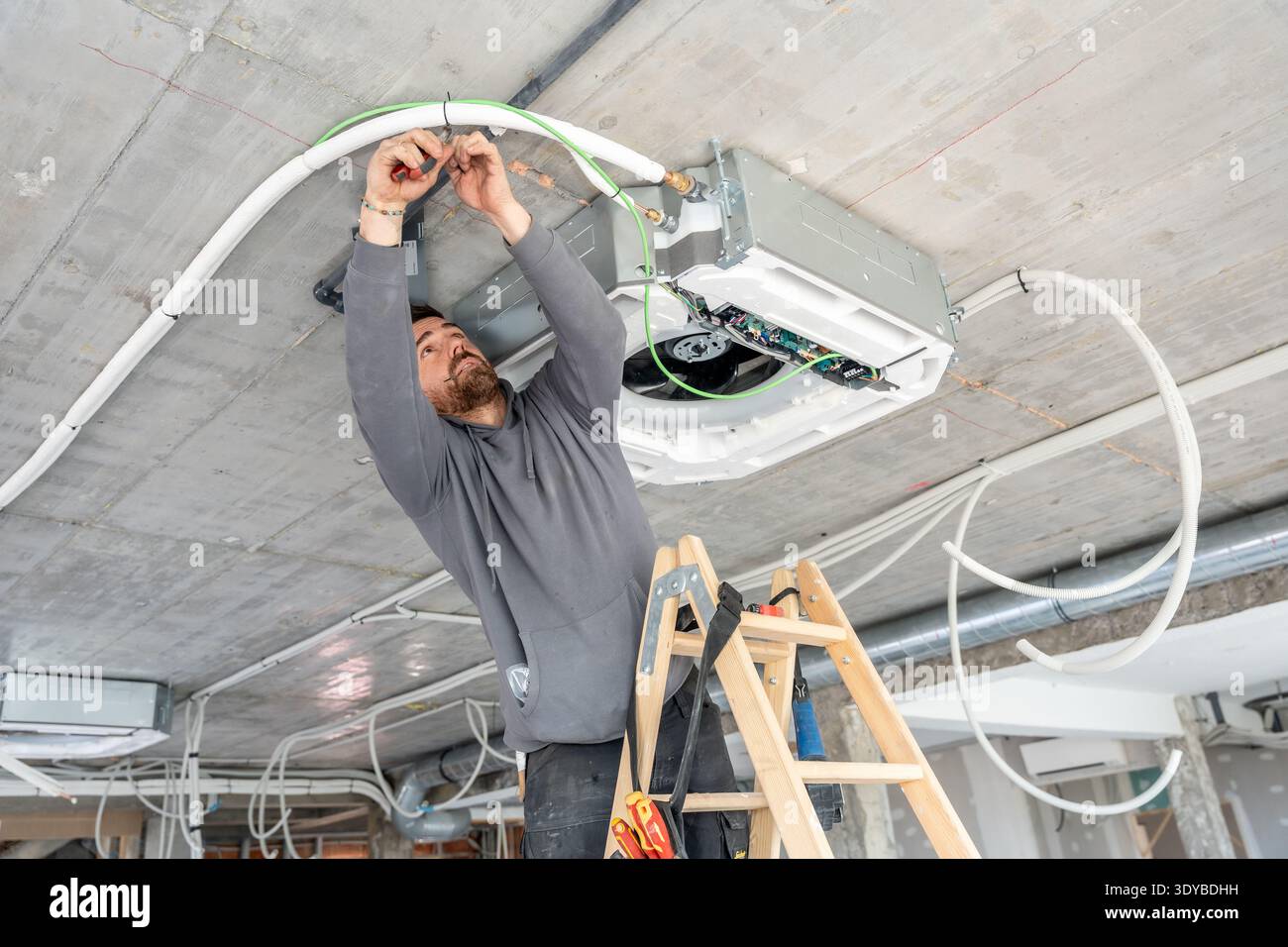 Hvac technician installing air conditioning system on ceiling Stock Photo