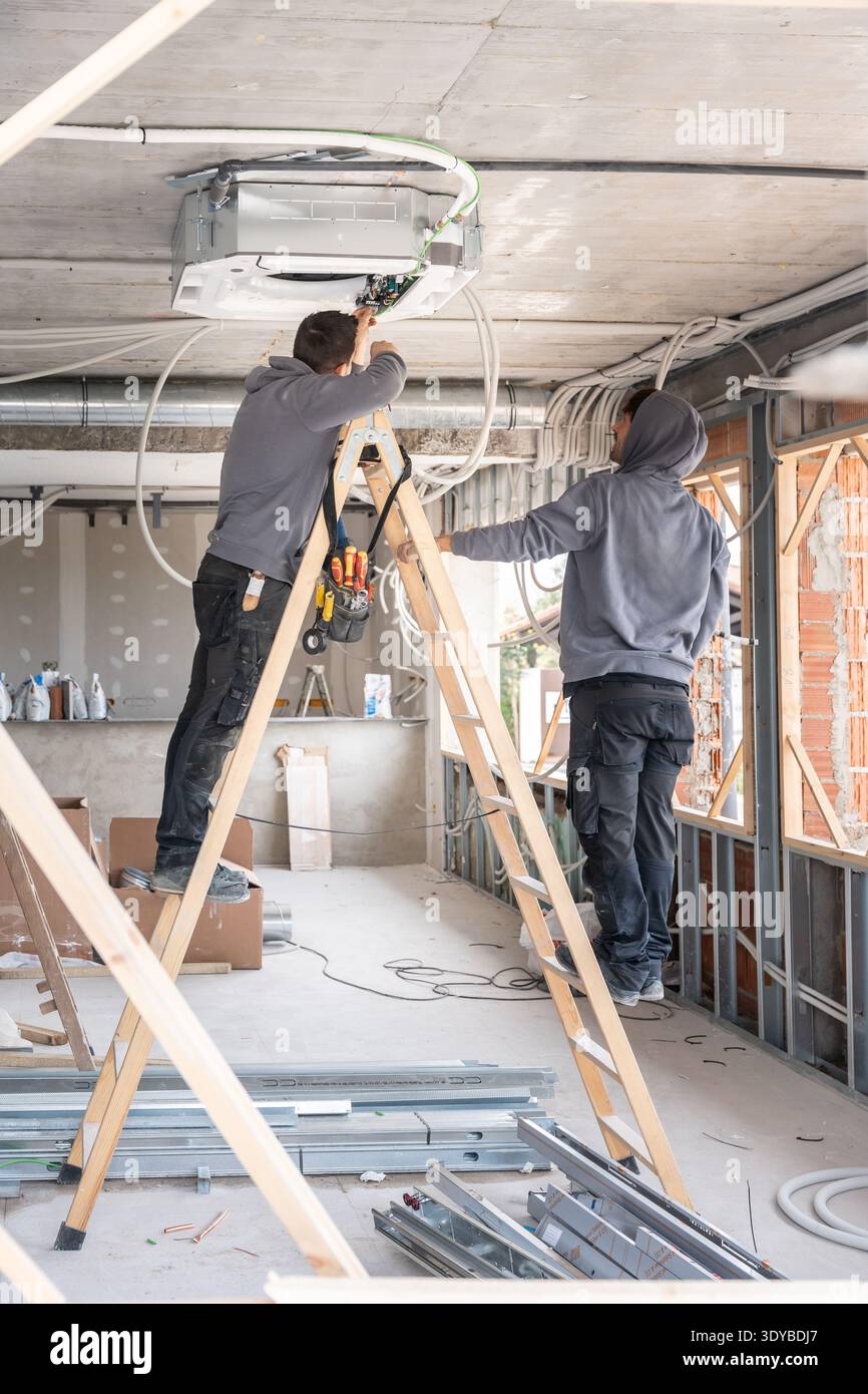 Air conditioning technicians installing hvac system during construction work Stock Photo