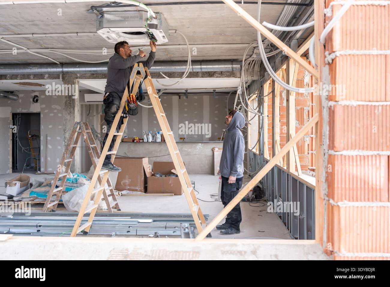Hvac technicians installing air conditioning unit on a construction site Stock Photo