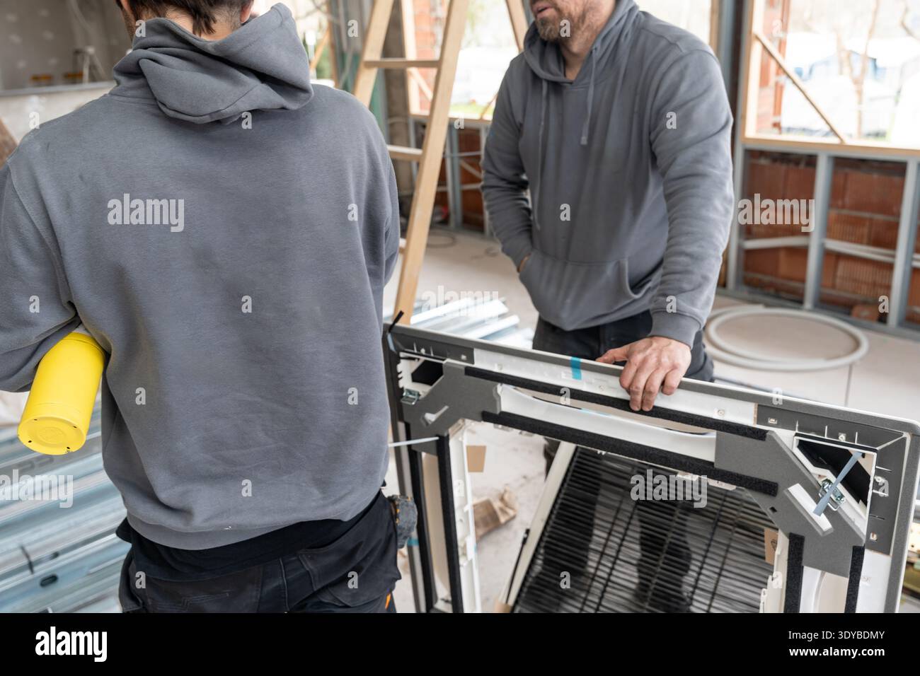 Hvac technicians installing air conditioning unit at construction site Stock Photo