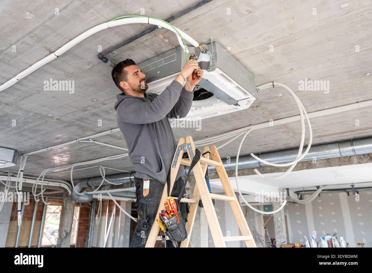 Hvac technician installing air conditioning unit on construction site Stock Photo