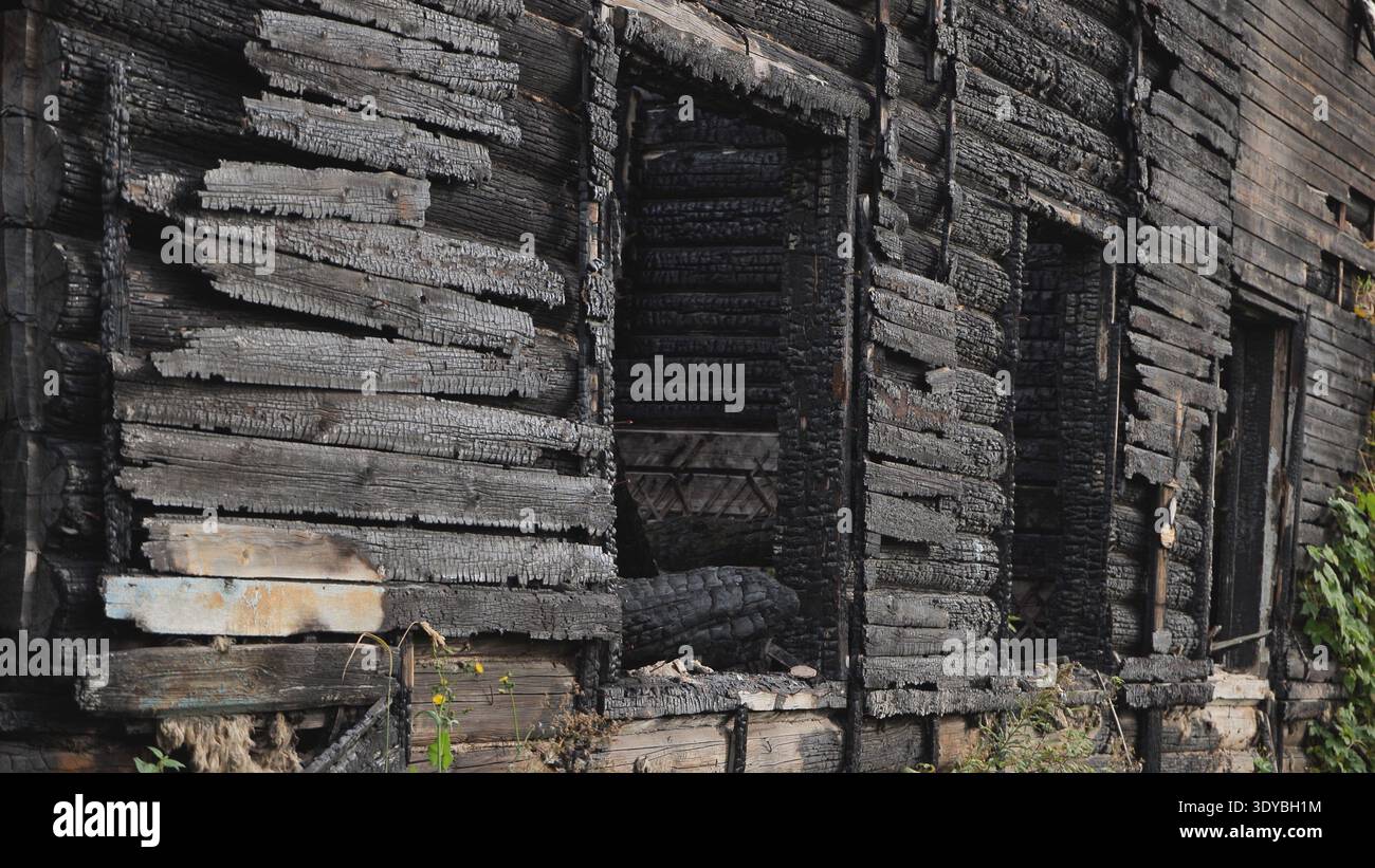 Burnt house structure showing extensive charring and fire damage Stock Photo