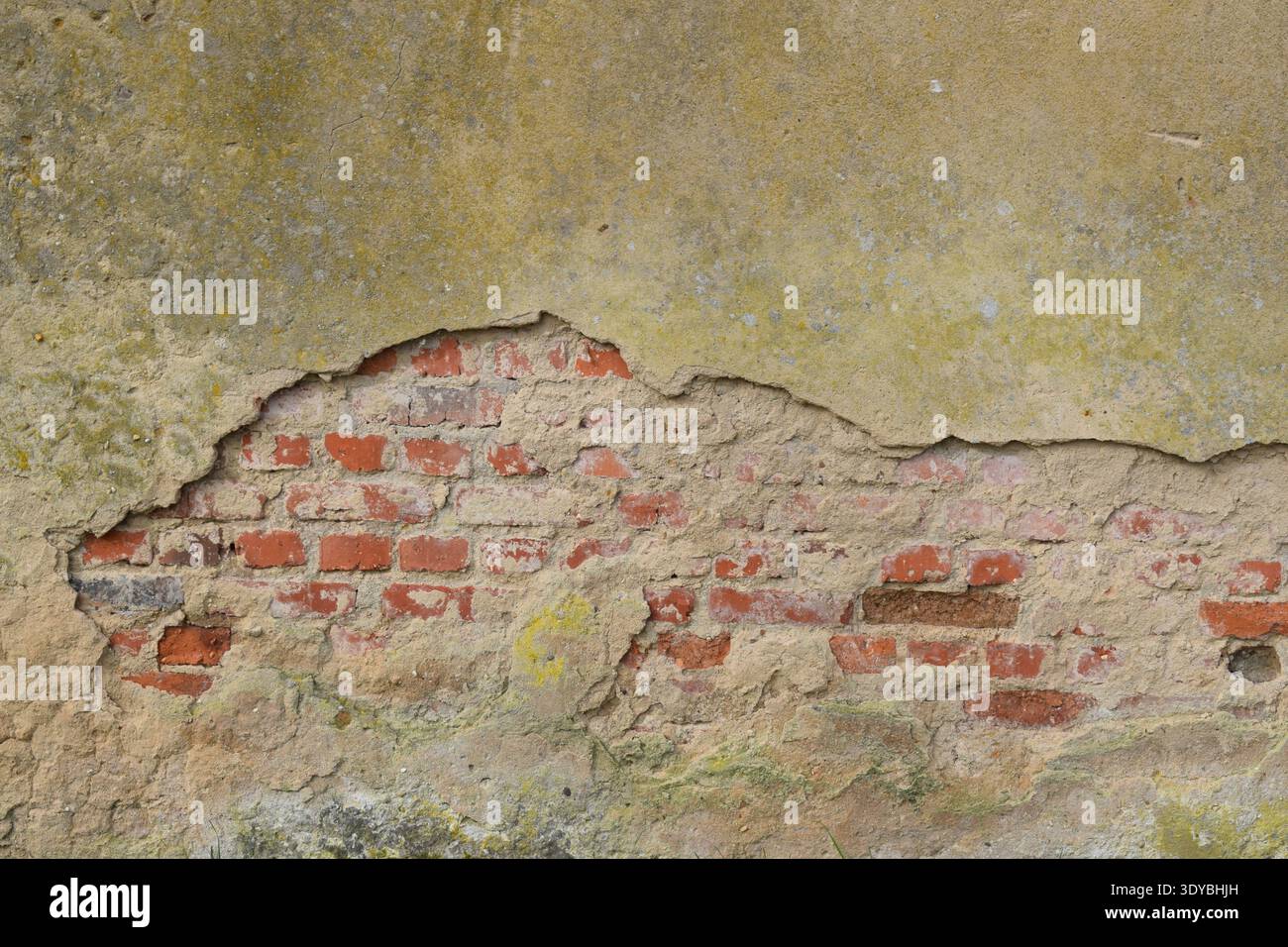 red bricks becoming visible in a broken wall Stock Photo