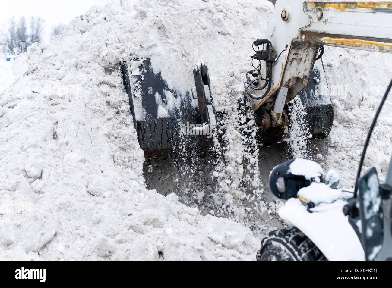 Excavator bucket bites into massive snow pile and throws slushy chunks ...