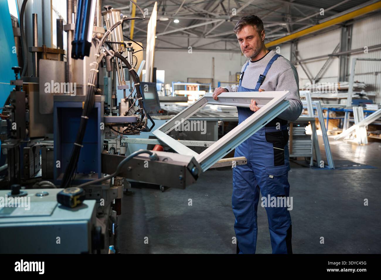 Professional production workers in coverall working with different PVC windows Stock Photo