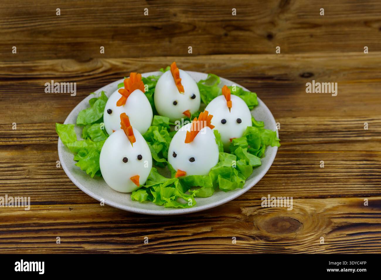 Funny easter breakfast with boiled eggs as chicks on wooden table Stock Photo
