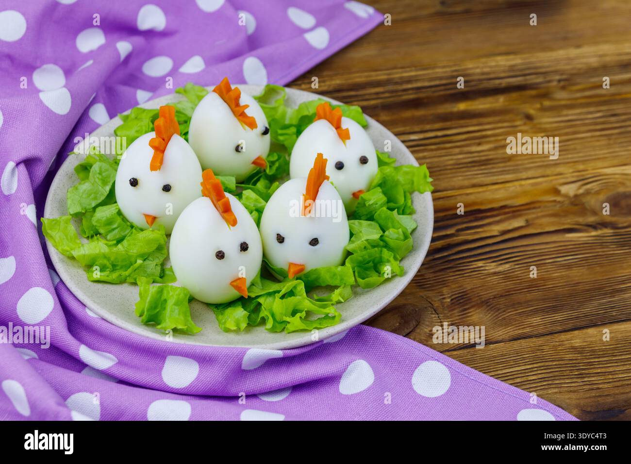Funny easter breakfast with boiled eggs as chicks on wooden table Stock Photo