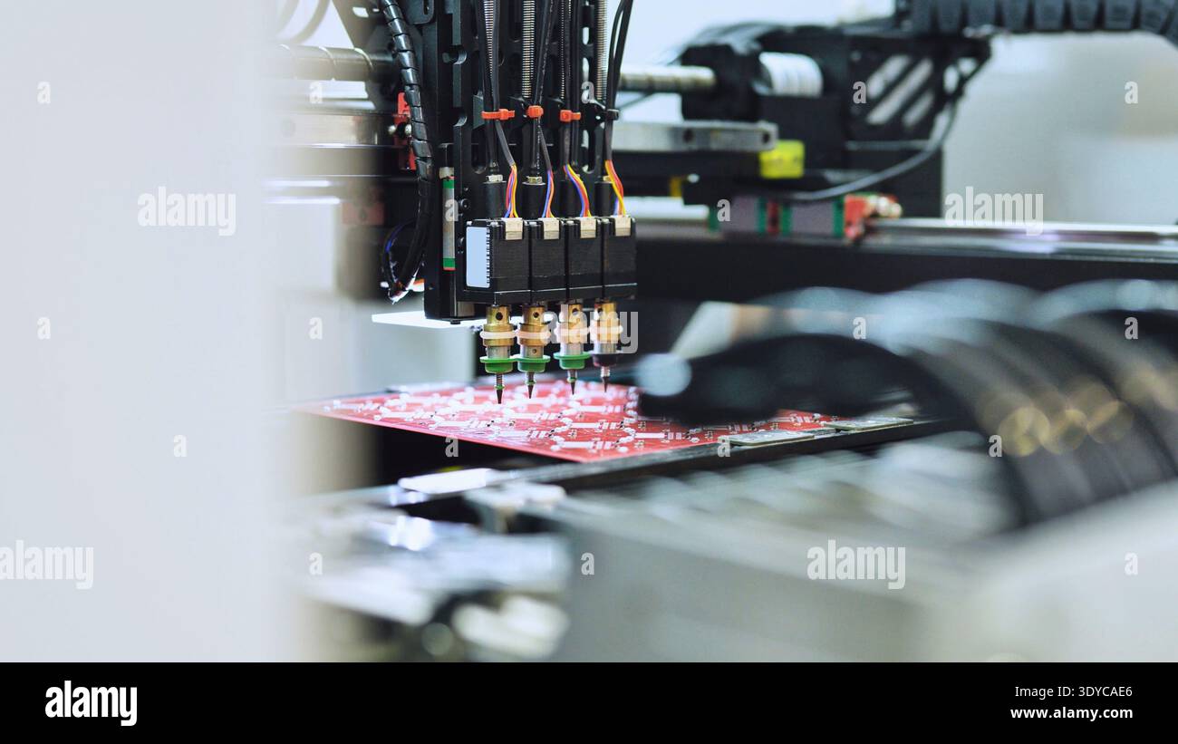 Automated machinery mounting electronic components on a red PCB Stock Photo