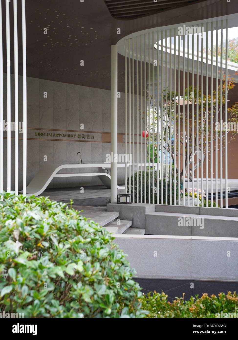 A peaceful scene of a modern pavilion with striking vertical slats overlooking a water feature. The image conveys architectural rhythm, quietude, luxu Stock Photo