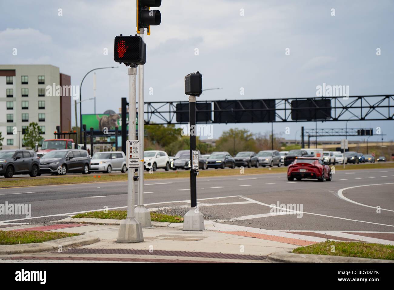Pedestrian crossing signal with red stop hand beside a wide urban ...