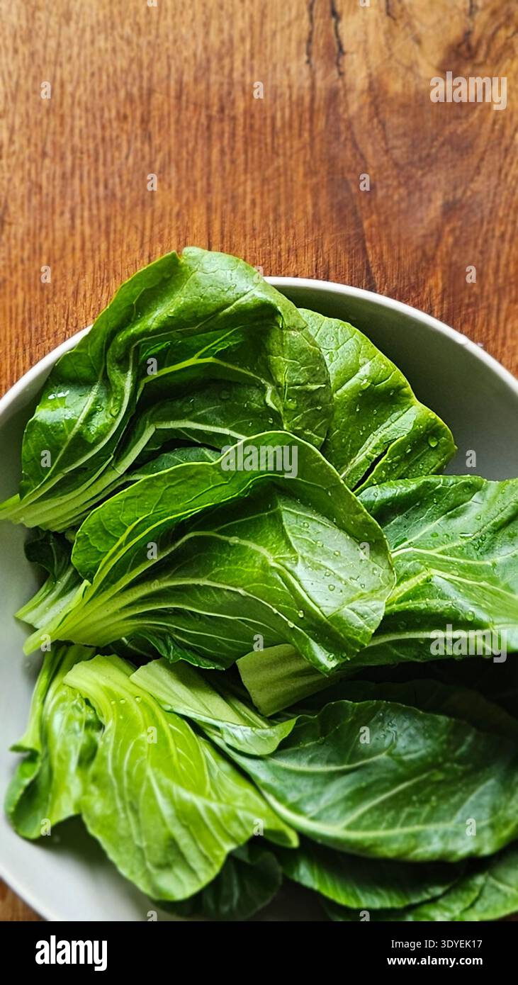 Fresh bok choy leaves in bowl on wooden table organic Asian leafy vegetable - Smartphone Captured Stock Image