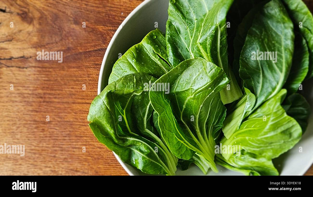Fresh bok choy leaves in bowl on wooden table organic Asian leafy vegetable - Smartphone Captured Stock Image