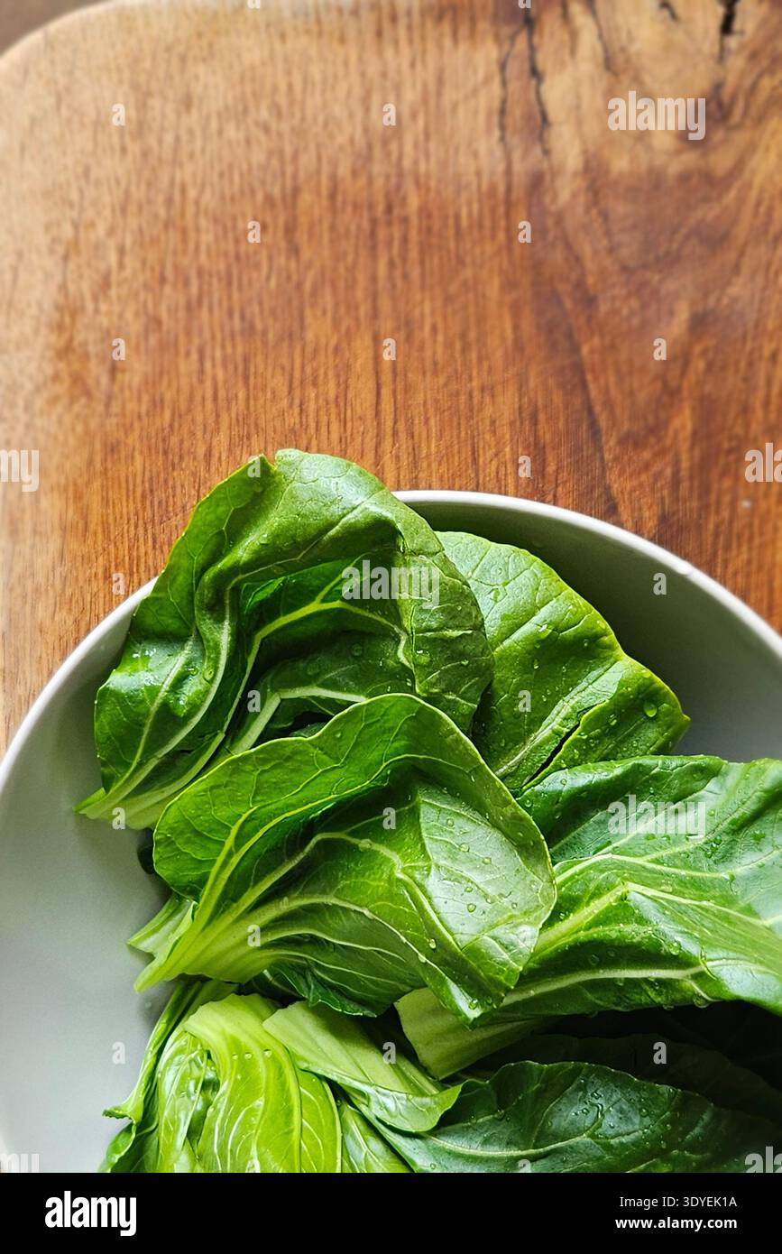 Fresh bok choy leaves in bowl on wooden table organic Asian leafy vegetable - Smartphone Captured Stock Image