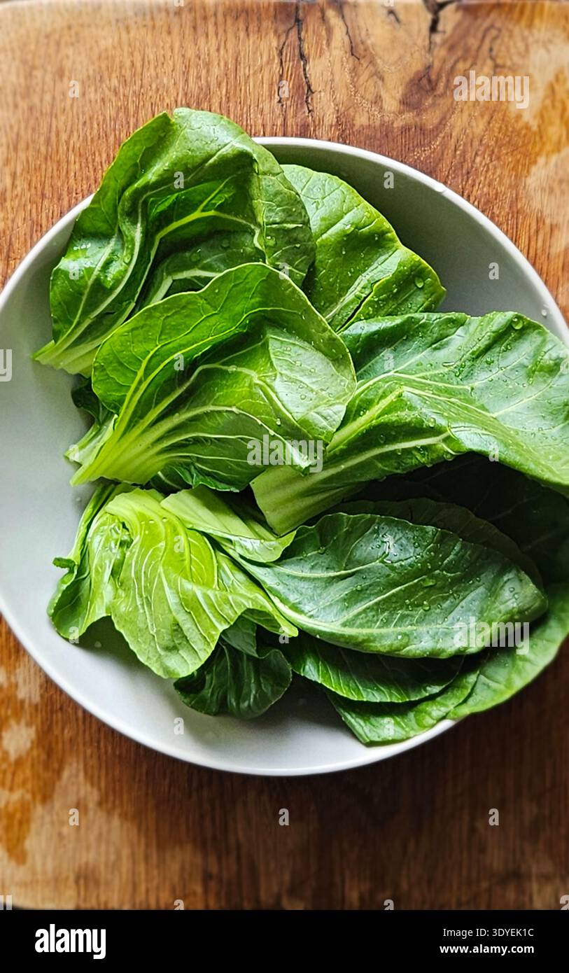 Fresh bok choy leaves in bowl on wooden table organic Asian leafy vegetable - Smartphone Captured Stock Image