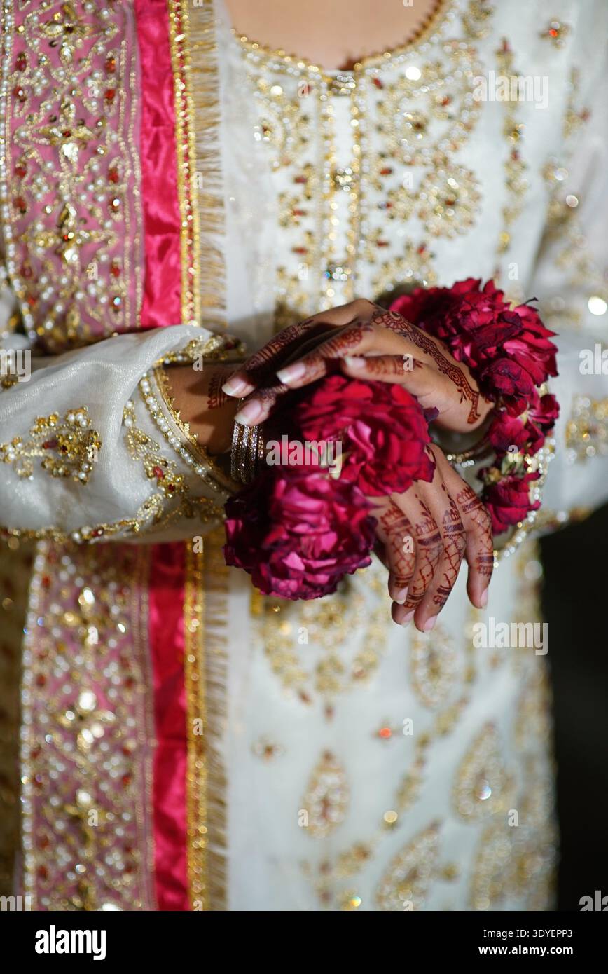 Pakistani bride showing intricate henna (mehndi) designs on her hands,  wearing traditional red floral bangles (gajra) and a white wedding dress  Stock Photo - Alamy