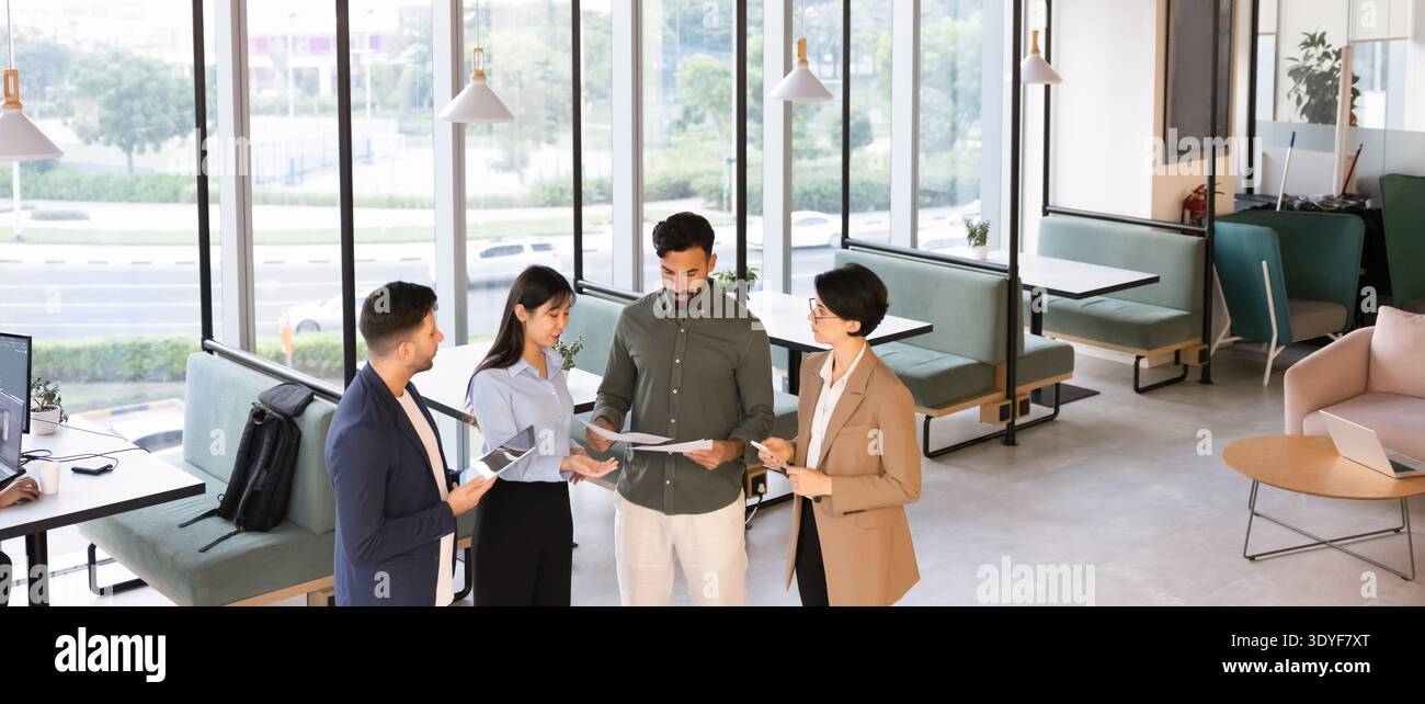Diverse professionals collaborating on paperwork and digital tablet in office Stock Photo
