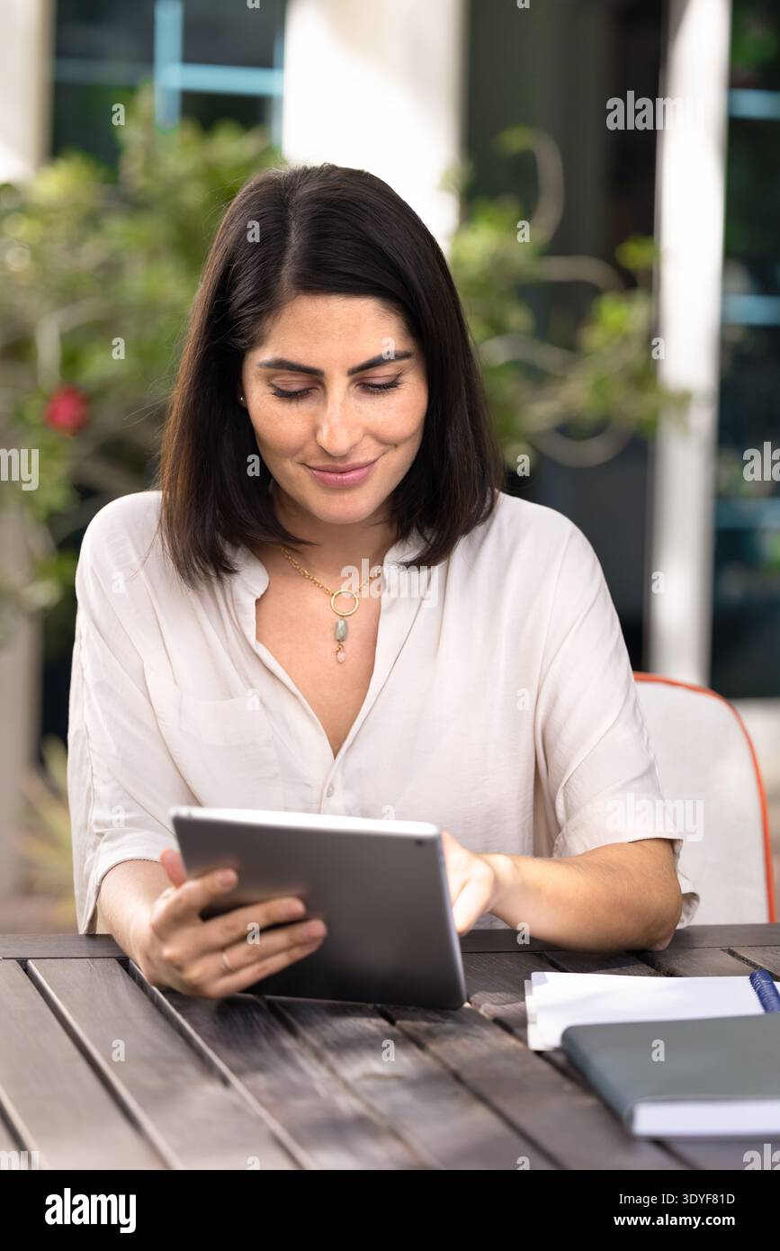 Positive young Latin woman using business application on digital tablet Stock Photo
