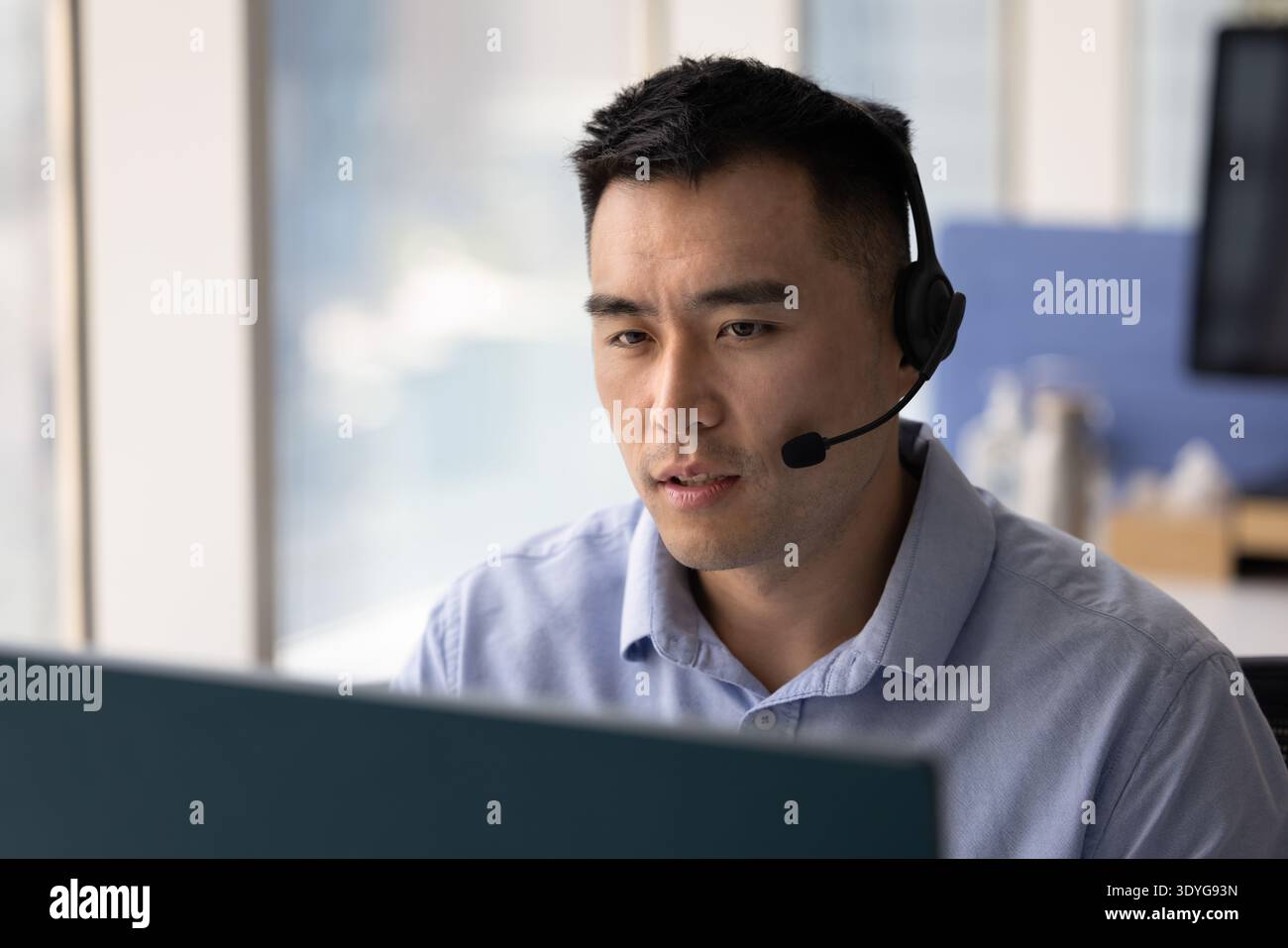 Young man wearing headset speaking by videocall using desktop pc Stock Photo