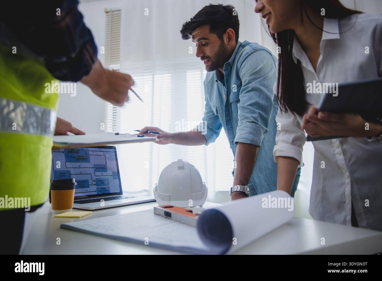 Architects and engineers discussing construction project with blueprint and safety helmet in office Stock Photo
