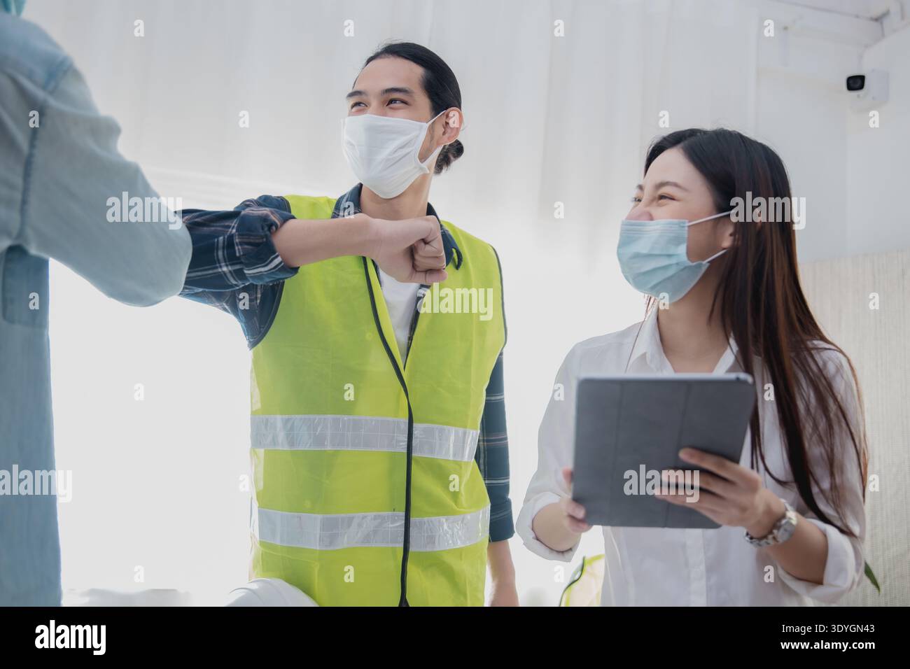Engineers greeting with elbow bump while wearing face mask during construction meeting Stock Photo