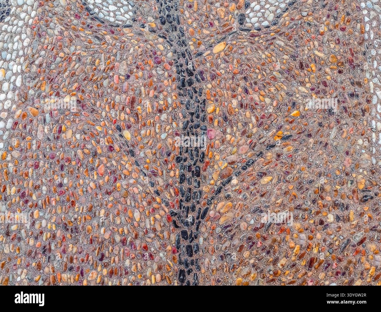 Decorative pattern on the sidewalk paved with small beach pebbles. Creative stone texture of a walking path Stock Photo